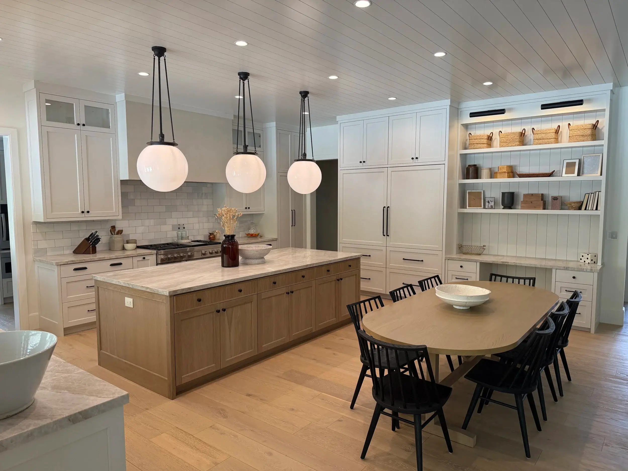 Custom kitchen cabinetry with large center island, pendant lighting, and open shelving