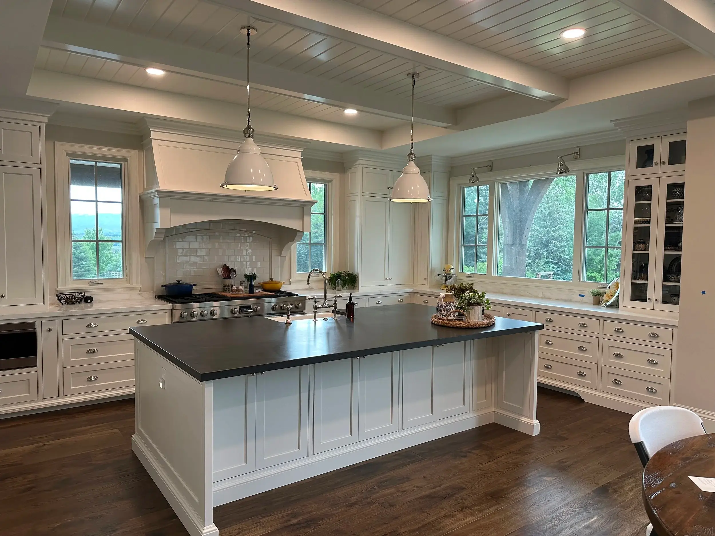 Bright white custom kitchen with large center island, pendant lighting, and floor-to-ceiling cabinetry