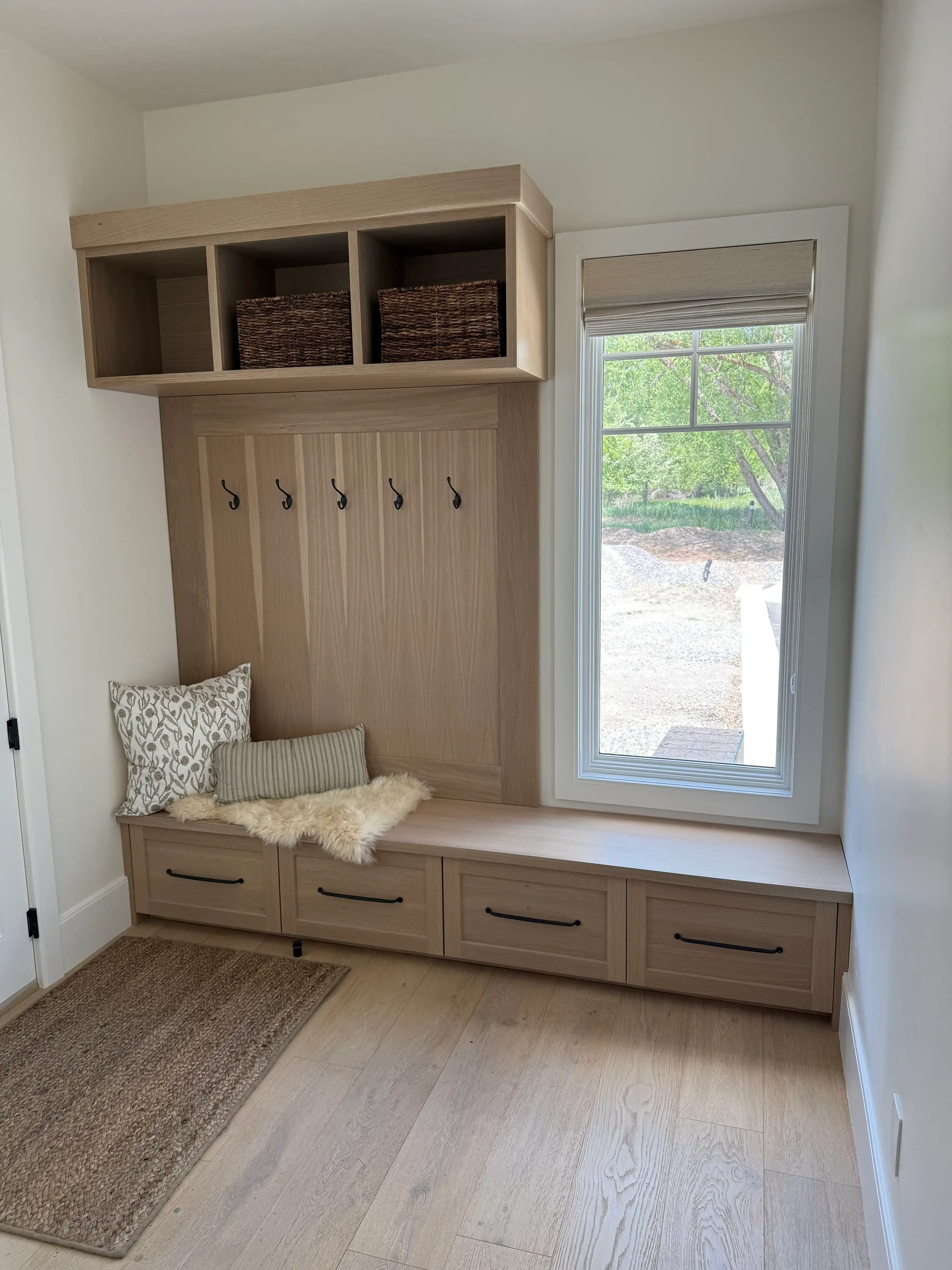Custom mudroom entry built-in with hall-tree paneling, coat hooks, overhead cubbies, and a bench seat with drawer storage.