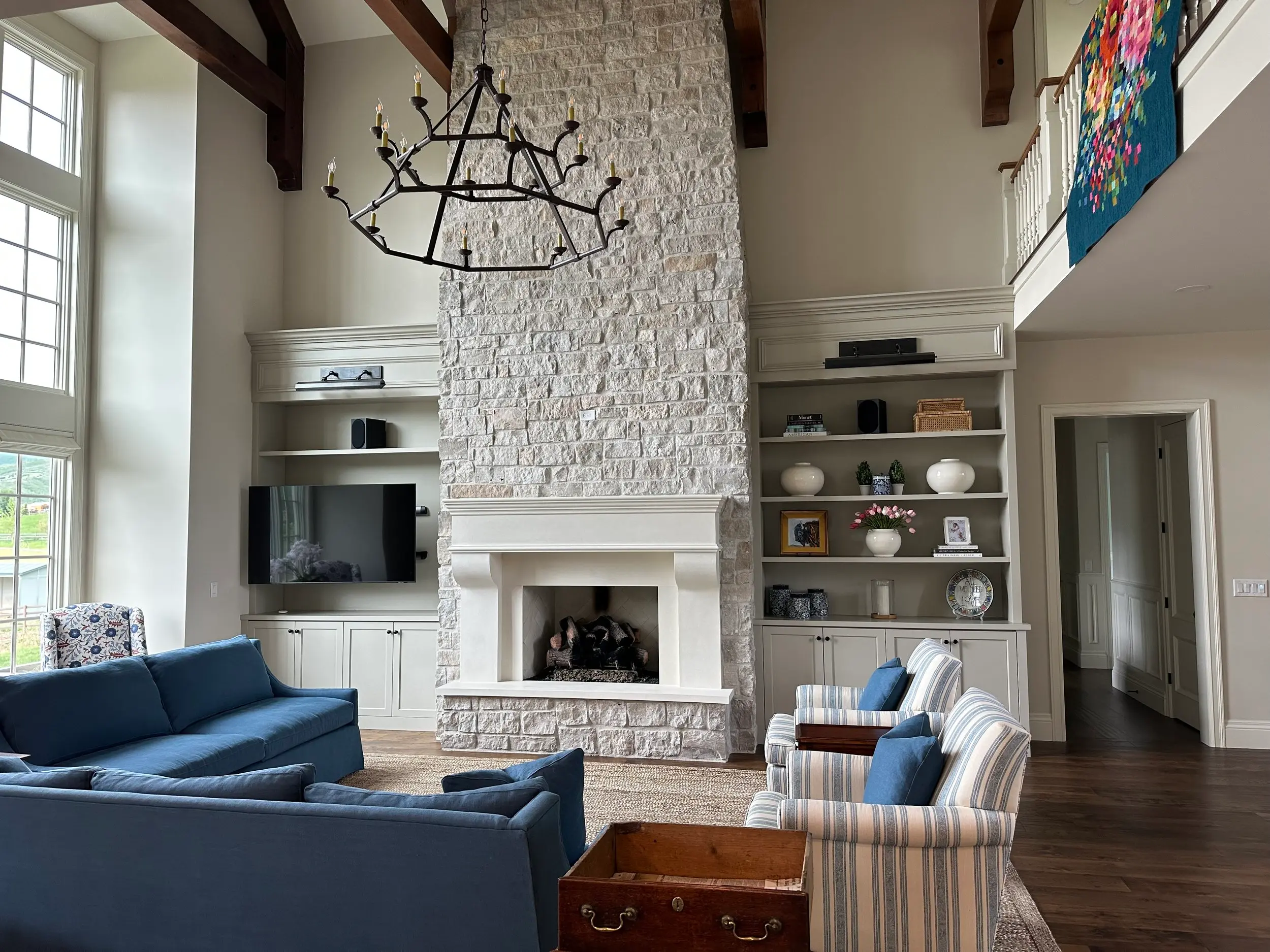 Custom built-in cabinetry flanking a two-story stone fireplace, with matching millwork detailing carried across a soaring great room.