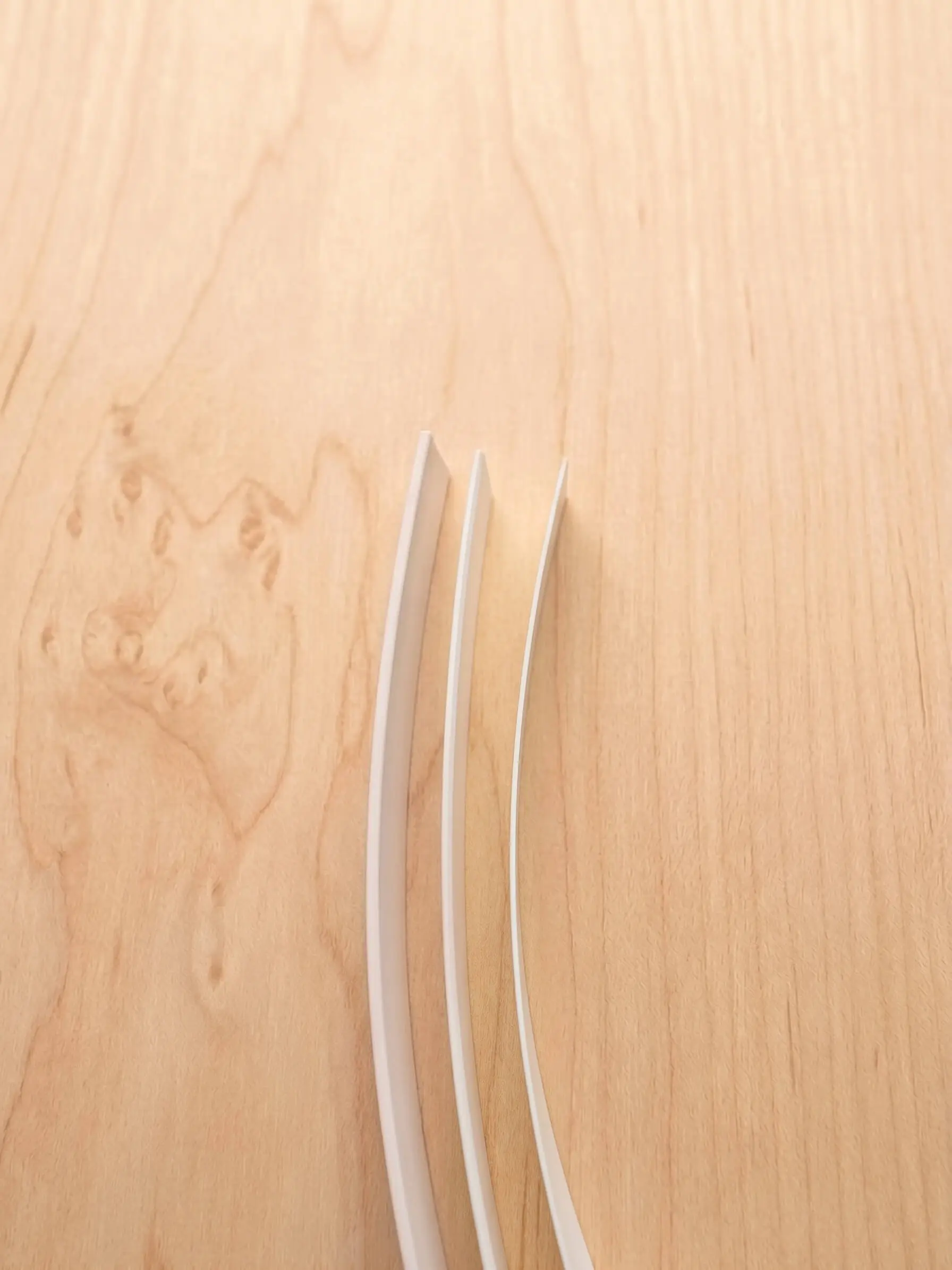 Close-up of matched edge banding applied to an engineered wood panel, showing seamless grain alignment in custom cabinet fabrication.