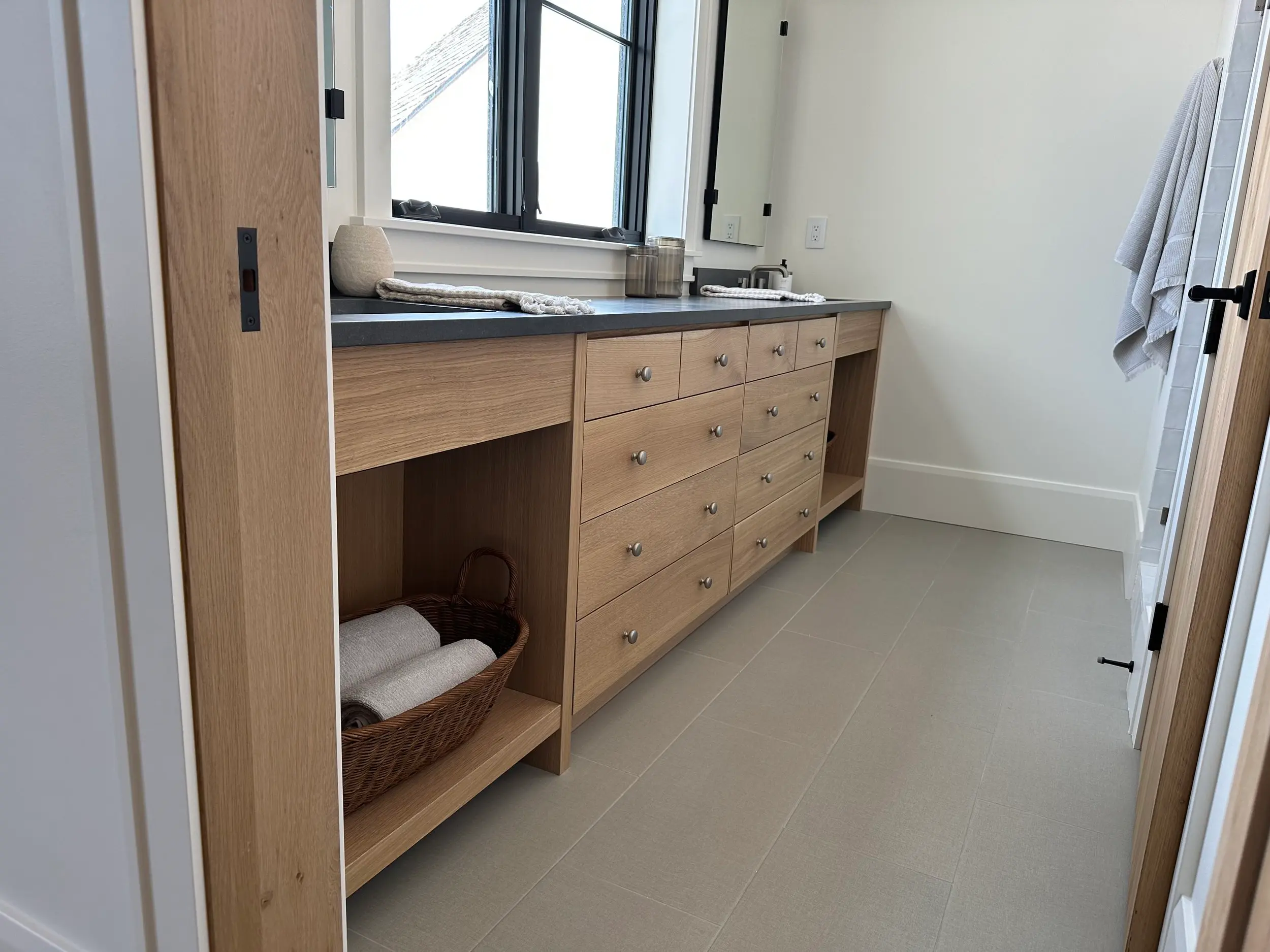 Natural wood bathroom renovation with compact vanity, patterned floor tile, and space-saving storage solutions designed for efficient functional layout.