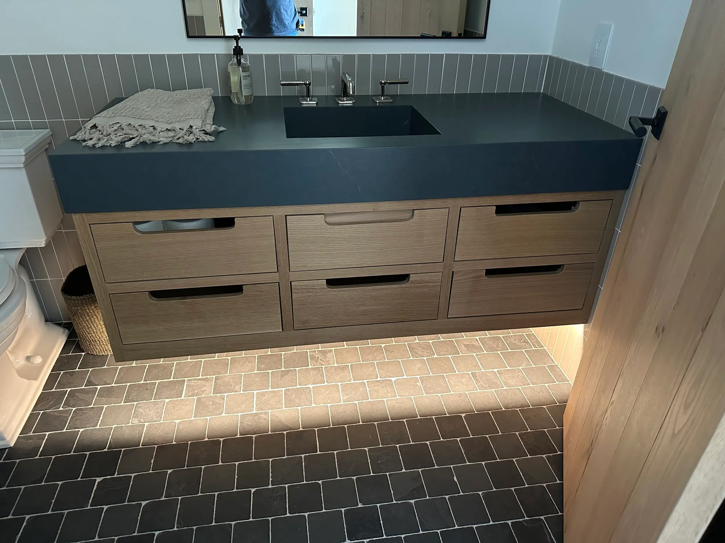 Transitional bathroom layout with natural wood vanity cabinetry, quartz countertop, and coordinated tile flooring in a warm neutral palette.